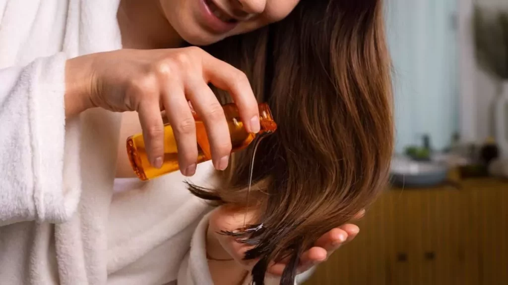 Mulher de cabelo longo liso e castanho aplicando reparador de pontas