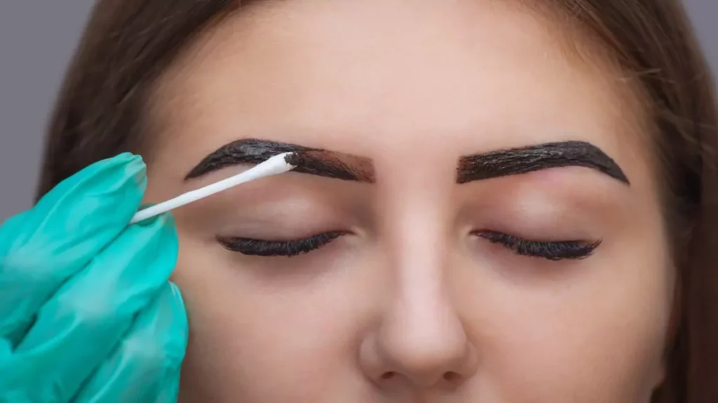 Foco em mulher aplicando henna para sobrancelha com os olhos fechados