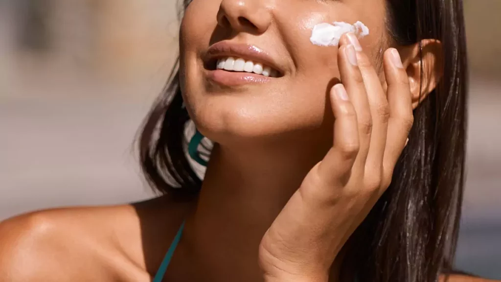 Mulher morena aplicando protetor solar para o rosto