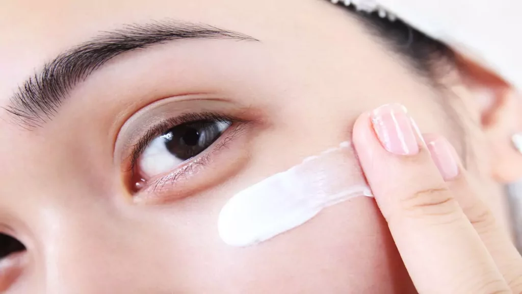 Mulher aplicando creme para olhos após o banho