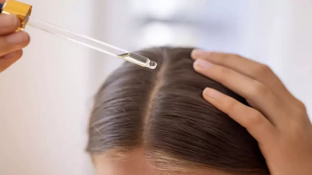 Foco em mulher aplicando tônico capilar na raiz do cabelo