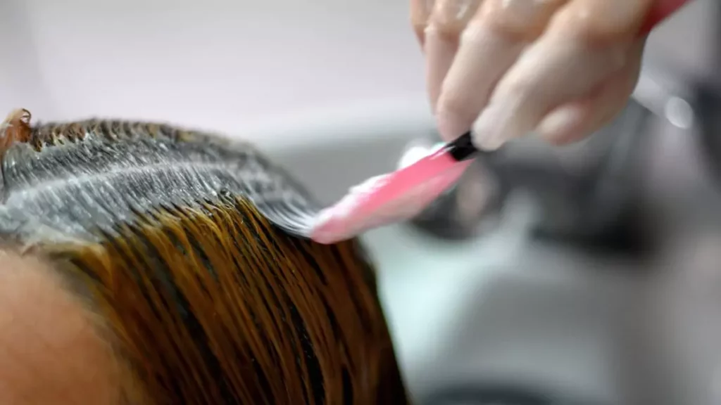 Mulher aplicando tinta de cabelo perto das raízes