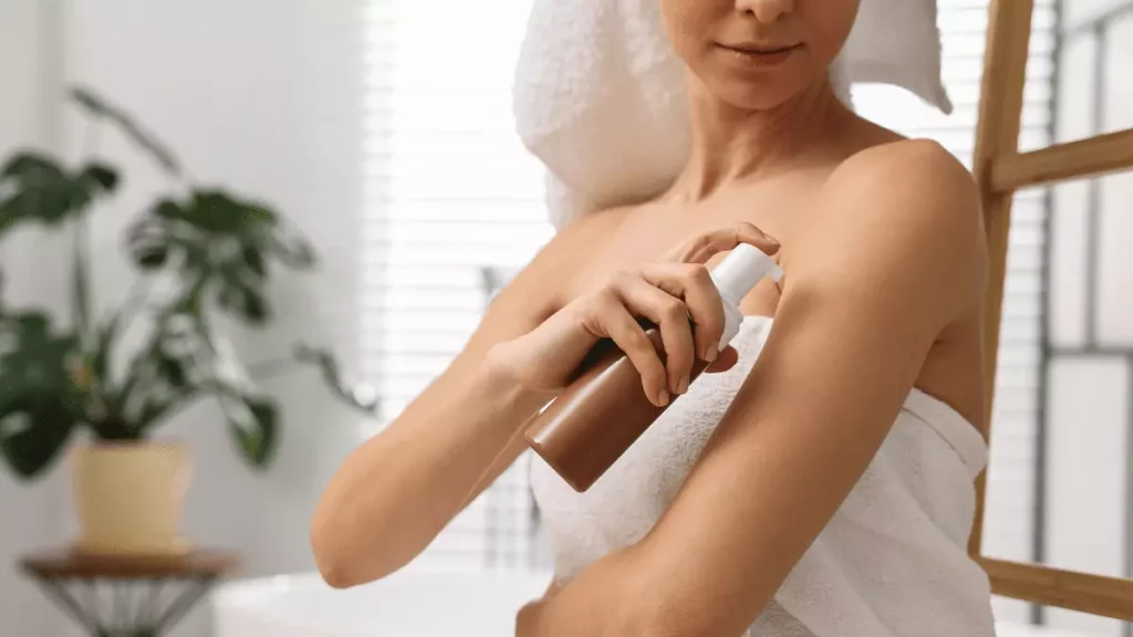 mulher aplicando autobronzeador com roupão branco