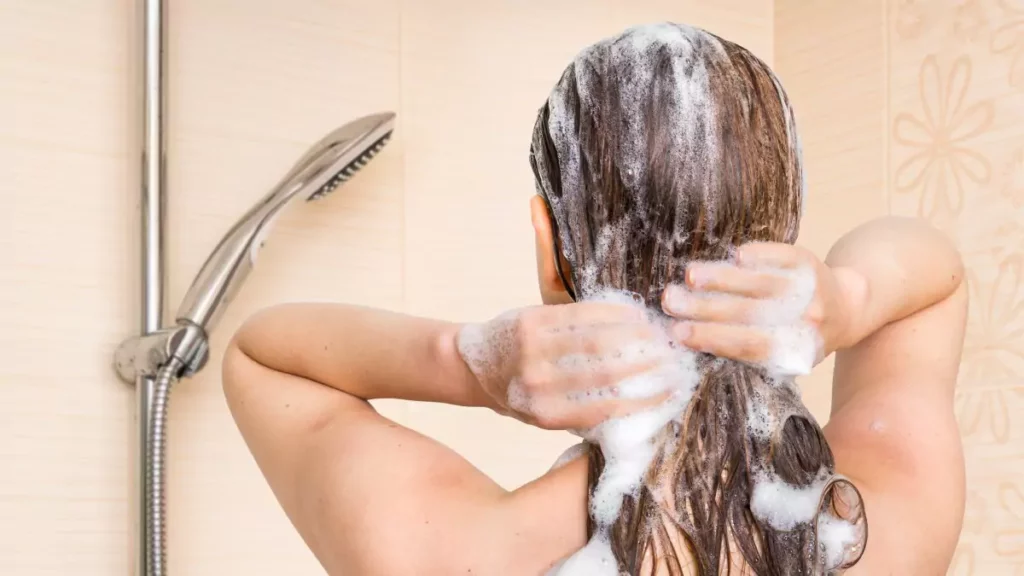 Mulher passando shampoo para crescer cabelo durante o banho