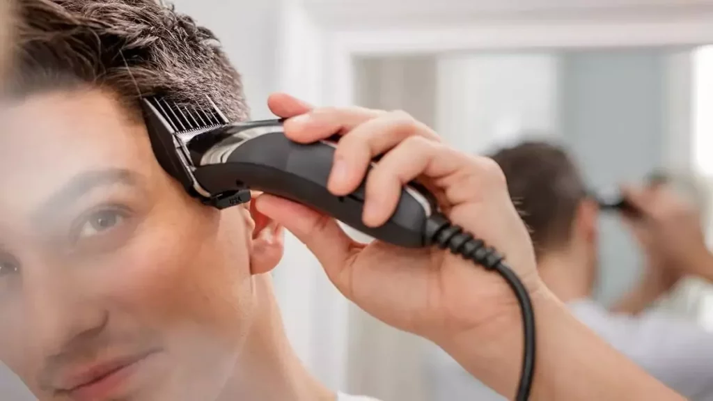 Homem usando máquina de cortar cabelo na lateral da cabeça